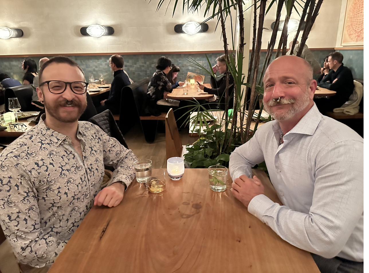 Barclay Barrios seated at a table in a fine dining restaurant with a friend across the table.