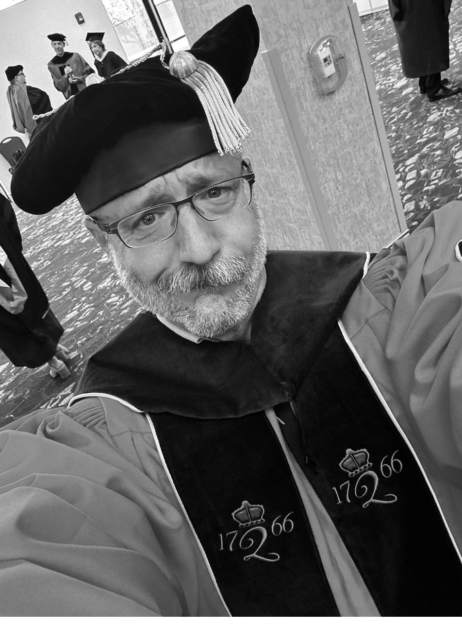 Barclay Barrios wearing academic regalia, cap and gown, at a university graduation ceremony.